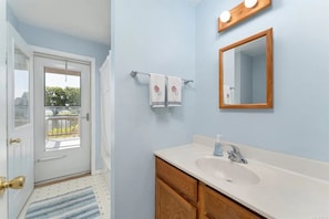 A bathroom with a white sink, wooden cabinets, a mirror, and a towel rack with decorative towels.