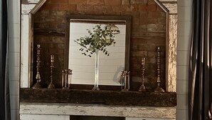 Una chimenea rústica con un marco de ladrillo blanco, una lámpara colgante y un florero con plantas.