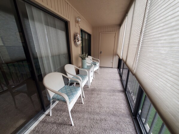 Un balcon avec deux fauteuils en osier, une petite table et une plante en pot.