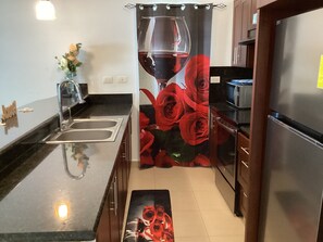 A kitchen with a stainless steel refrigerator, a sink, and a microwave. There is a decorative shower curtain with a rose design. - Beachfront Jr Penthouse *Amazing Views*1 min walk to Beach/Restaurants Elevator  (Sosúa)