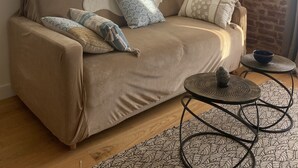 A cozy living room with a beige sofa, two round mirrors, a brick accent wall, and a small round table with a bowl.