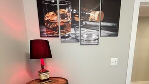A wooden barrel as a side table with a red lamp, three framed pictures on the wall, and a wooden floor. - Bright, Cheery Home steps from Shops & Nightlife! (Louisville)