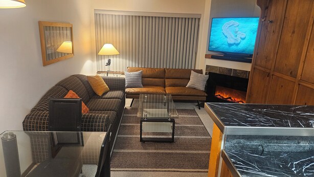 A living room with a sofa, a coffee table, a TV, and a fireplace.