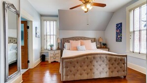 A bedroom with a large bed, a ceiling fan, a nightstand, a dresser, and a mirror. - Walk to Restaurants & Shops of Downtown Miamisburg (Miamisburg)