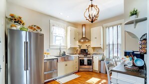 A modern kitchen with stainless steel appliances, a dining area with a wooden table, and a chandelier. - Walk to Restaurants & Shops of Downtown Miamisburg (Miamisburg)