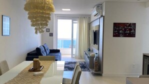 Un salon moderne avec un coin repas, un lustre et une vue sur l’extérieur.