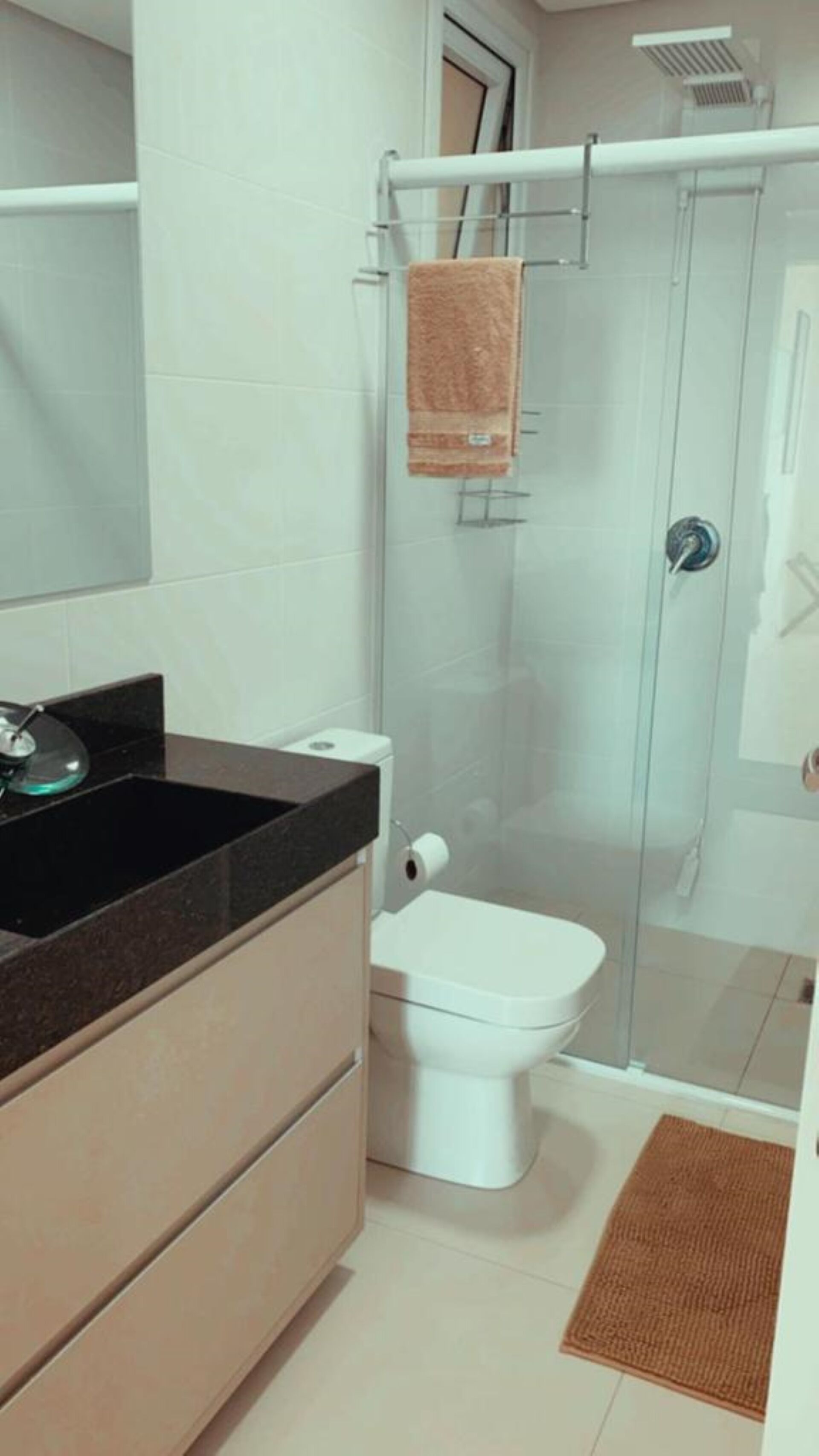 A modern bathroom with a glass shower enclosure, a white toilet, and a black sink with a mirror.