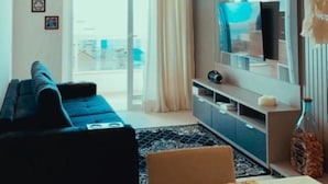 Un salon moderne avec un canapé, un téléviseur et une grande fenêtre.