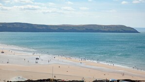 Una playa con cielo despejado, mar tranquilo y colinas a lo lejos.