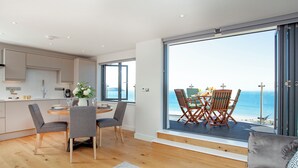 Un espacio moderno para vivir con cocina, comedor y balcón con vistas al mar.