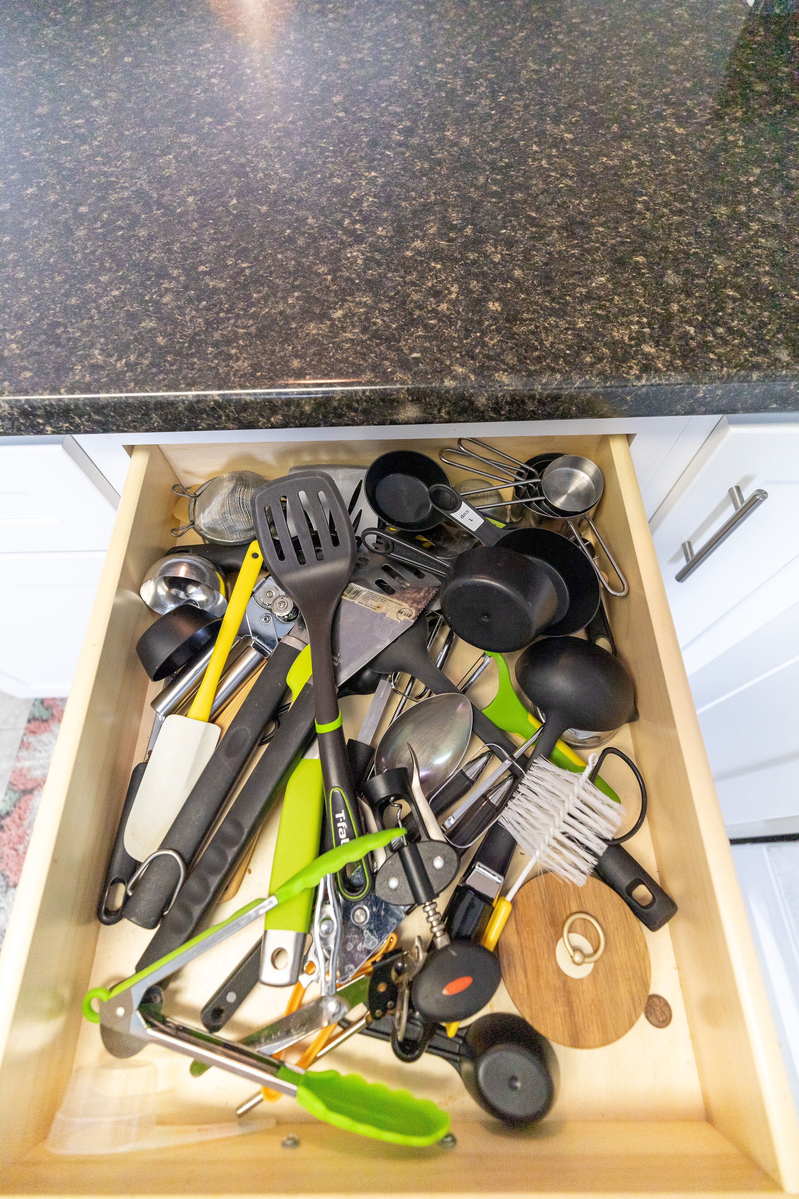 A drawer filled with kitchen utensils and tools, including spatulas, tongs, and a grater.
