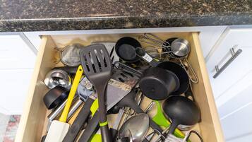 A drawer filled with kitchen utensils and tools, including spatulas, tongs, and a grater.