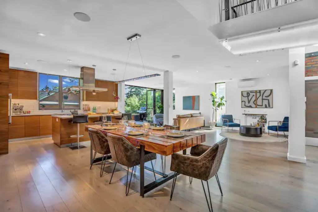 Una cocina amplia y moderna con una isla grande, armarios de madera y un comedor con una mesa larga y sillas.