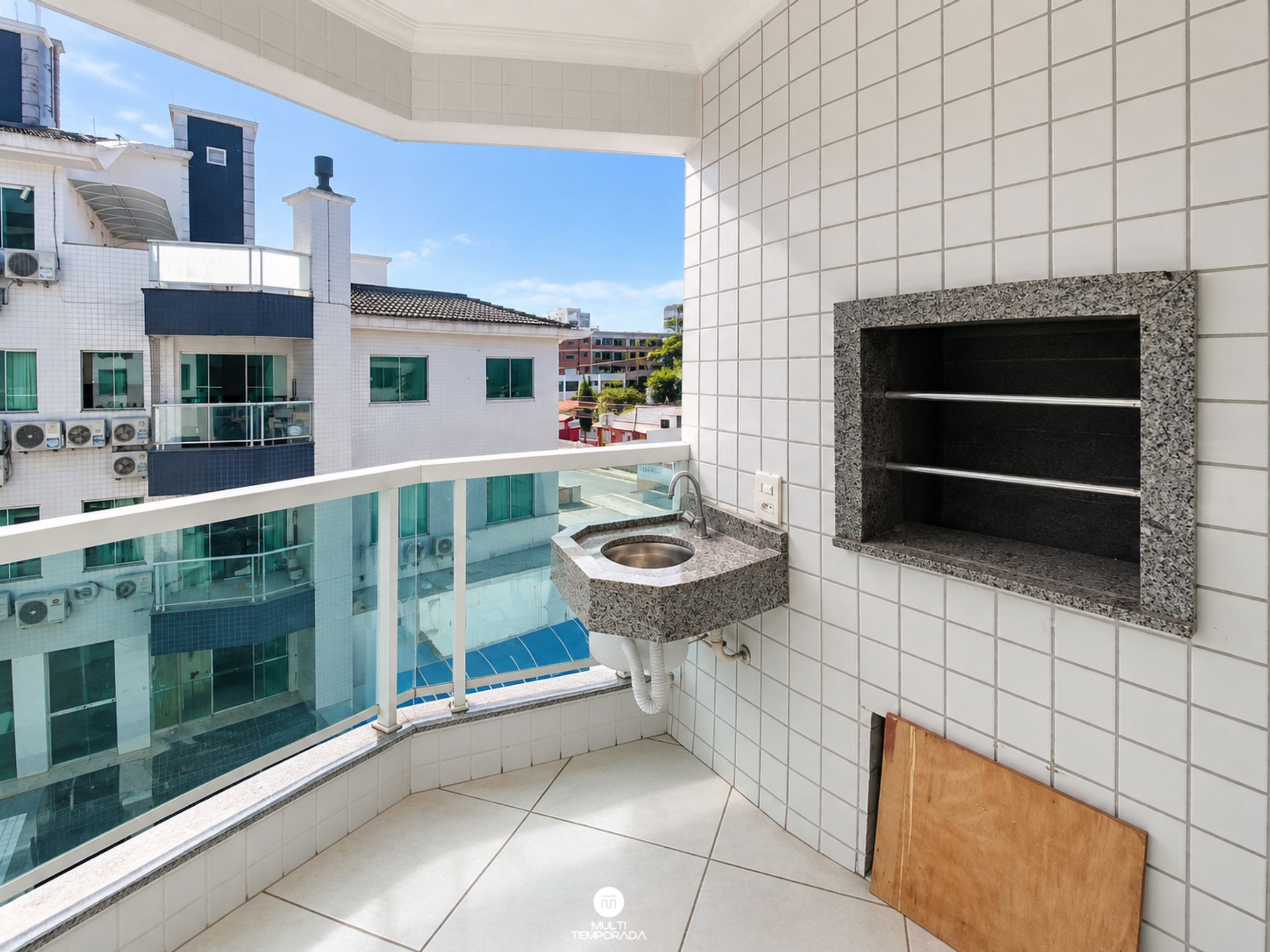 A modern balcony with a glass barrier, a built-in sink, and a view of the cityscape.