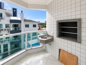 A modern balcony with a glass barrier, a built-in sink, and a view of the cityscape.