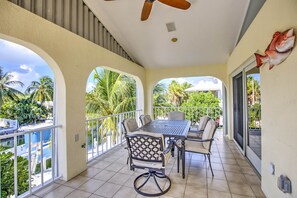 A balcony with a table and chairs, a ceiling fan, and a view of palm trees. - Private Pool, Hot Tub, Boat Dock, Putting Green (Marathon)