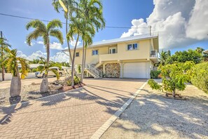 A two-story house with a garage, a stone wall, and a small tree in the front yard. - Private Pool, Hot Tub, Boat Dock, Putting Green (Marathon)