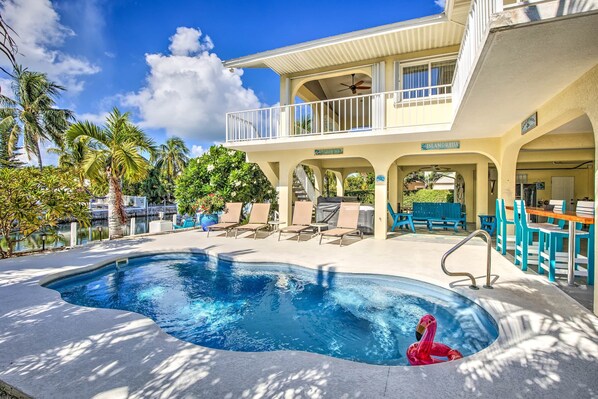 A pool area with lounge chairs, a pool, and a building with a sign reading "City County Beach". - Private Pool, Hot Tub, Boat Dock, Putting Green (Marathon)