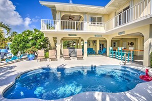 A pool area with lounge chairs, a hot tub, and a two-story building with balconies. - Private Pool, Hot Tub, Boat Dock, Putting Green (Marathon)