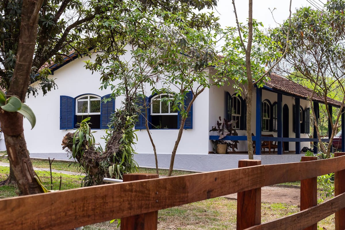Un bâtiment blanc avec des volets bleus et une clôture en bois au premier plan.