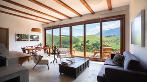 A spacious living room with a large sliding glass door leading to a balcony with a scenic mountain view. - Fazenda Santa Vitória (Queluz)