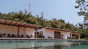 A poolside area with two white buildings, each with a pergola and seating. - Fazenda Santa Vitória (Queluz)