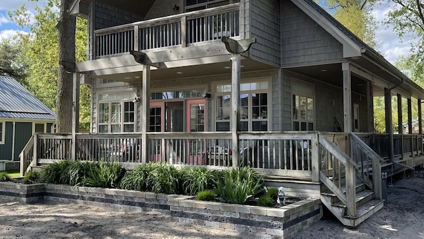 A two-story wooden building with a balcony, a covered porch, and a dirt driveway.
