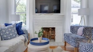 Un salon avec une cheminée, un téléviseur et deux canapés à motifs.