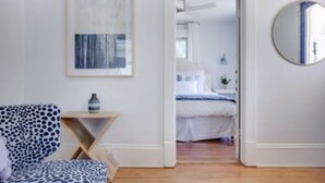 Une pièce comprenant un lit, une chaise, une petite table et un tableau encadré accroché au mur.