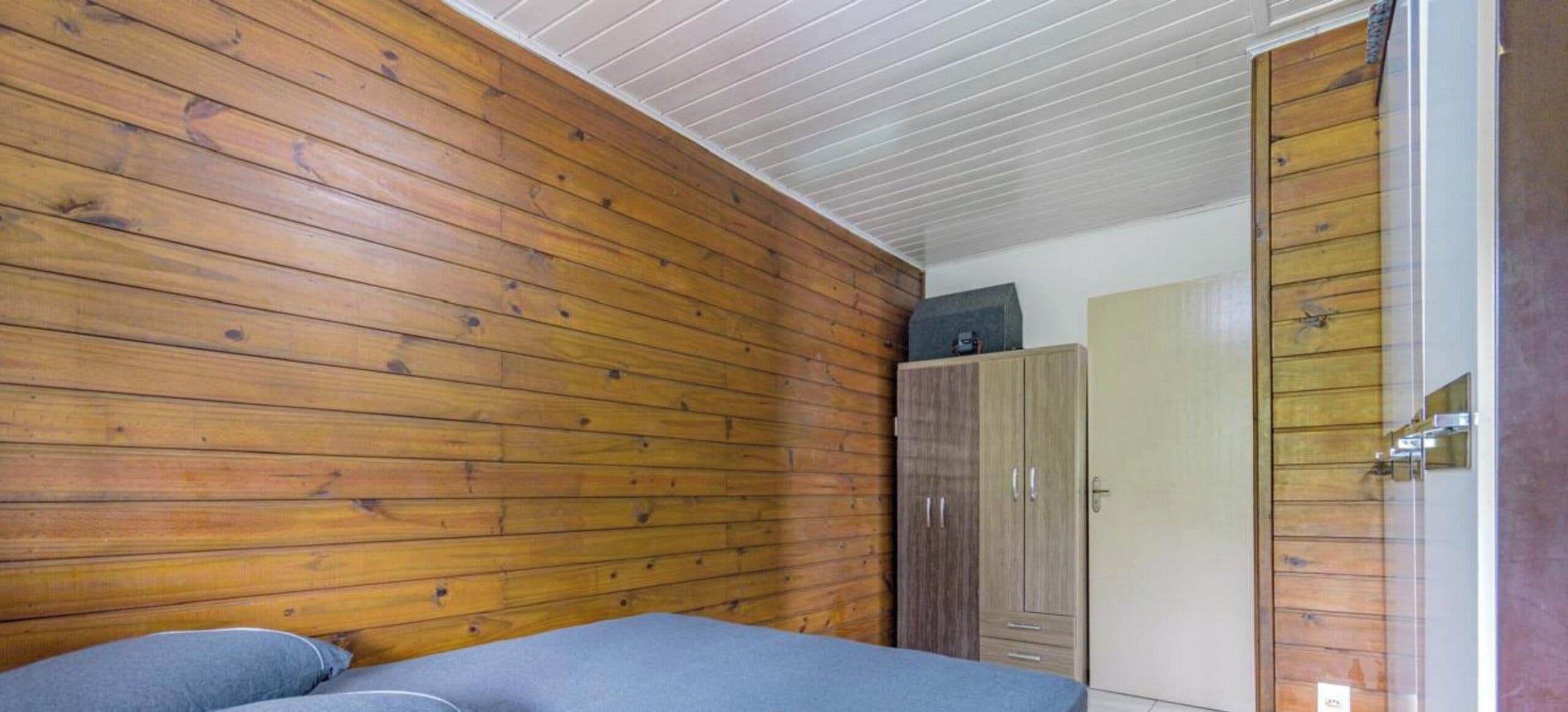 Una habitación con paneles de madera, una cama con colchón azul y un armario.
