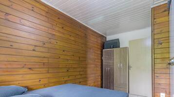 Una habitación con paneles de madera, una cama con colchón azul y un armario.