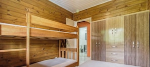 A bunk bed room with wooden walls and a wardrobe with mirrored doors.