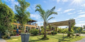 A modern house with a wooden pergola, lush greenery, and a hammock. - Casa com Piscina em Gov Celso Ramos - SC (Governador Celso Ramos)