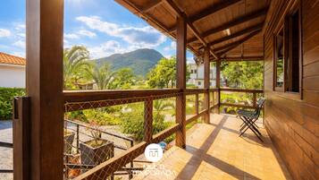 Varanda de madeira com vista para uma montanha e vegetação.