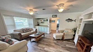A spacious living room with a wooden floor, a sofa, a coffee table, and a television.