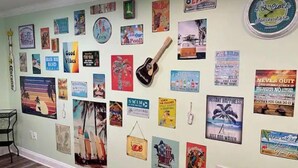 A wall with various posters and signs, including a clock, a surfboard, and motivational quotes.
