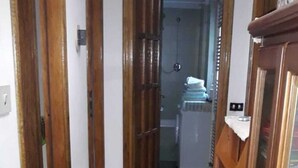 A narrow hallway with patterned floor tiles, wooden doors, and a glimpse of a bathroom in the background. - Apartment on the 2nd Floor 5 min from the spa (Saint-Vincent)