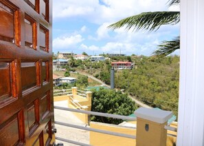 Une vue depuis un balcon donnant sur un quartier résidentiel, avec des maisons et de la verdure.