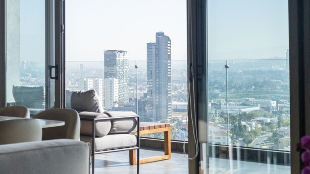 A modern living room with a large sliding glass door leading to a balcony with a city view. - Most Luxurious Property in Puebla - Ultra Luxurious 4 Bedrooms 4.5 Bath - Pool (Tx)
