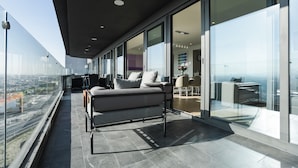 A modern balcony with a sofa and chairs, large glass doors, and a city view. - Most Luxurious Property in Puebla - Ultra Luxurious 4 Bedrooms 4.5 Bath - Pool (Tx)