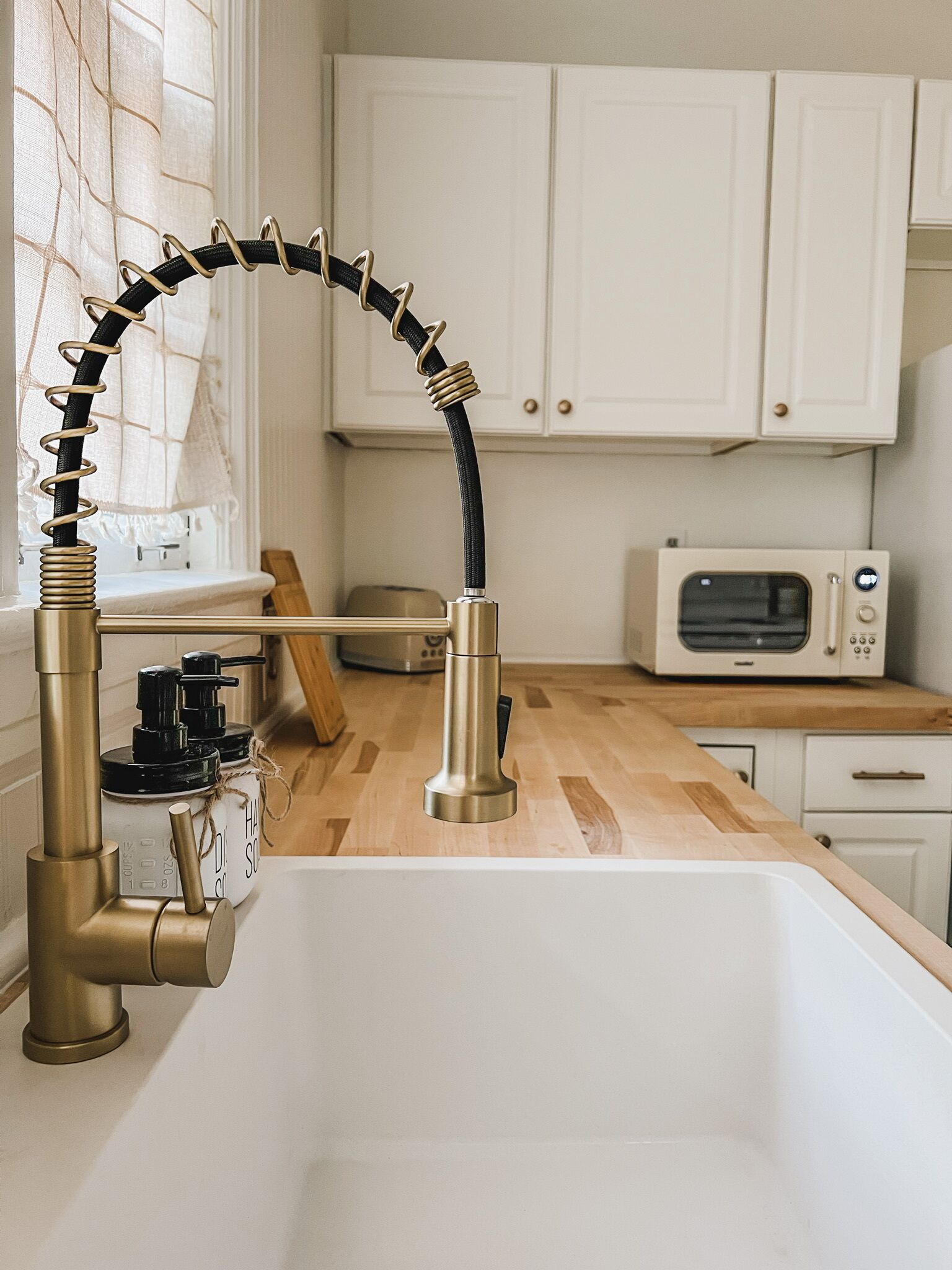 A kitchen with a modern sink, a microwave, and wooden cabinets.