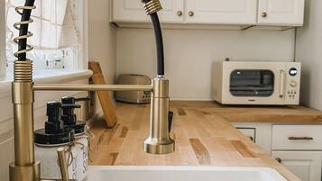 A kitchen with a modern sink, a microwave, and wooden cabinets.