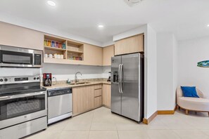A modern kitchen with stainless steel appliances, wooden cabinets, and a built-in dishwasher.