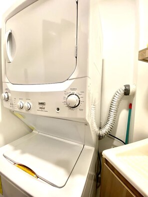 Una lavatrice a carica frontale con manopole di controllo e un tubo di ingresso dell'acqua.