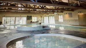 An indoor swimming pool with a tiled deck, a small hot tub, and a staircase leading to a higher level. - Golf resort for Labor Weekend (Klamath Falls)