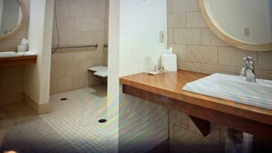 A bathroom with a wooden vanity, a round mirror, a towel rack, and a hand dryer. - Golf resort for Labor Weekend (Klamath Falls)