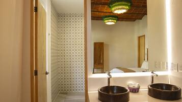 A bathroom with two round sinks, a mirror, and a green chandelier.