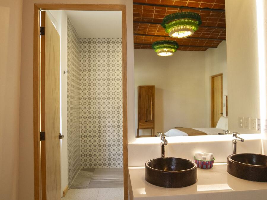 A bathroom with two round sinks, a mirror, and a green chandelier.