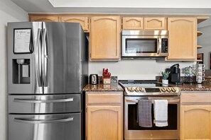 A kitchen with stainless steel appliances, wooden cabinets, and granite countertops.
