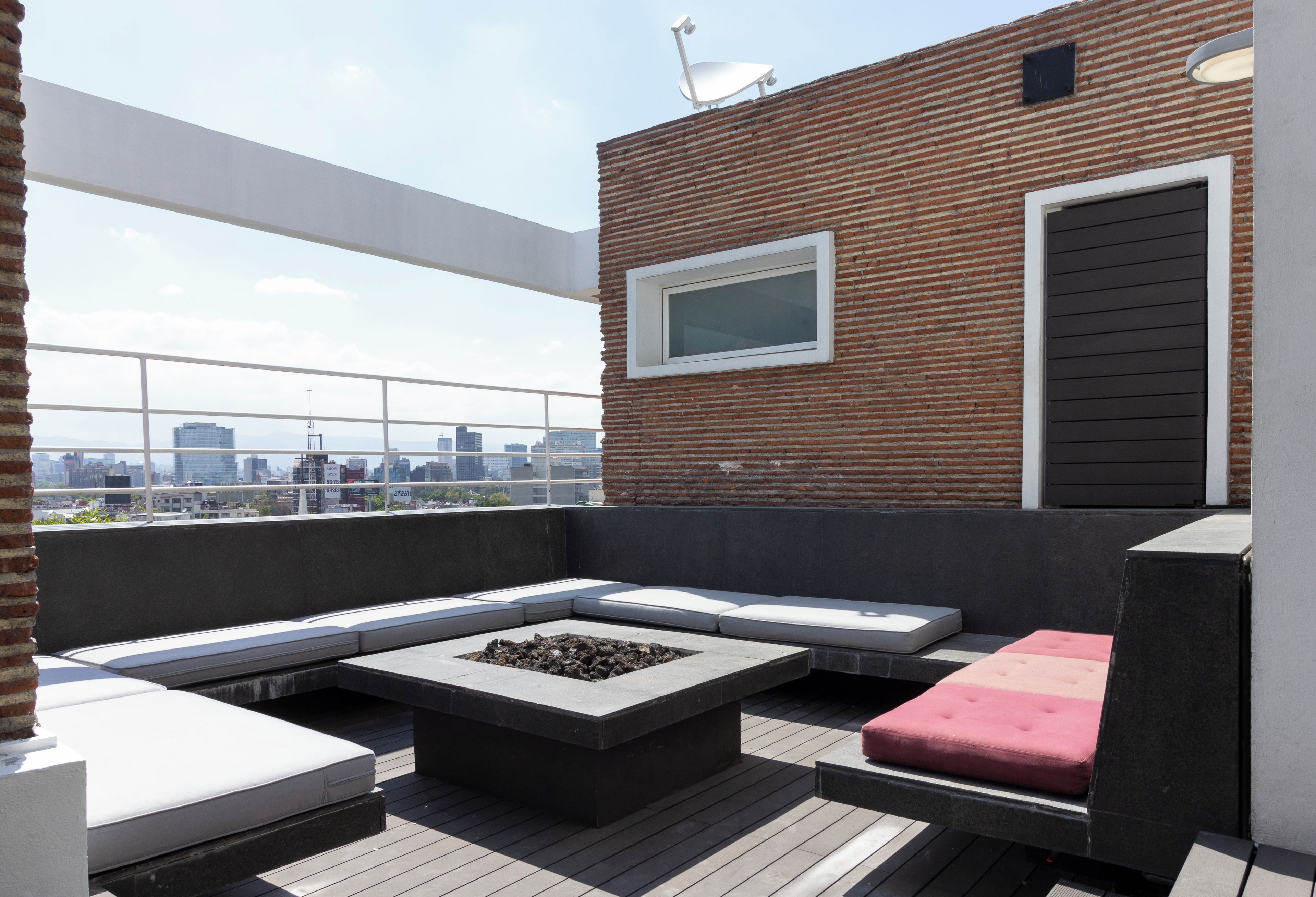 Una terraza en la azotea con un área de estar, una chimenea y vistas del horizonte de la ciudad.